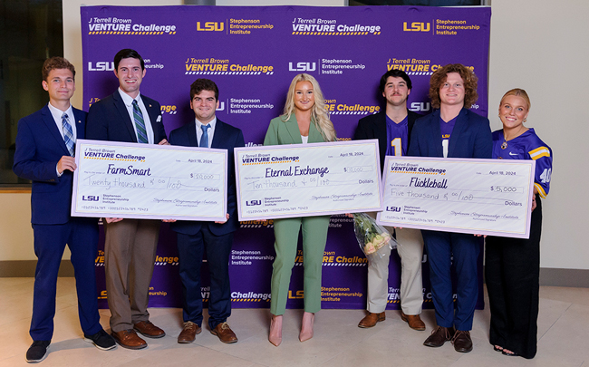 Three teams for LSU students hold large cardboard checks displaying the money they just one in an entrepreneurship pitch competition.