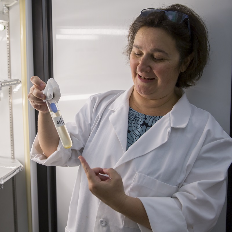 a woman in a lab coat holds a test tube