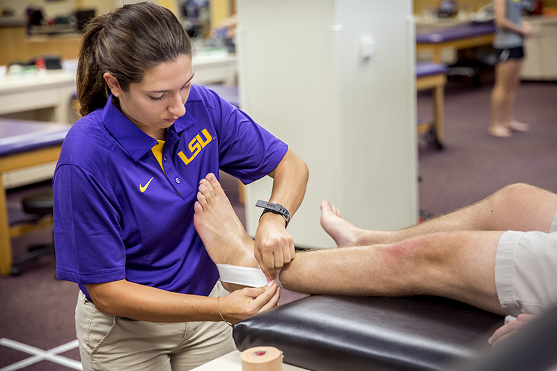 photo of female in LSU purple polo wrapping an ankle