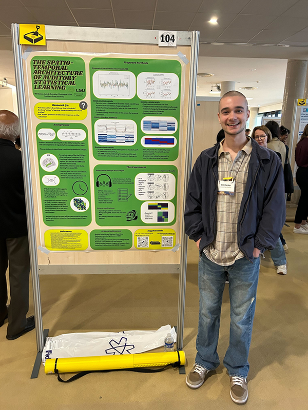 Photo of student standing next to research poster at a conference presentation.