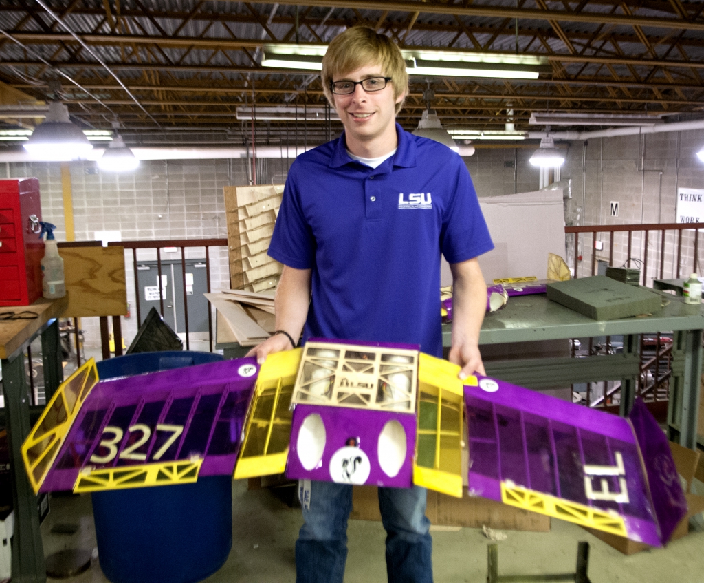student holding purple and gold model plane