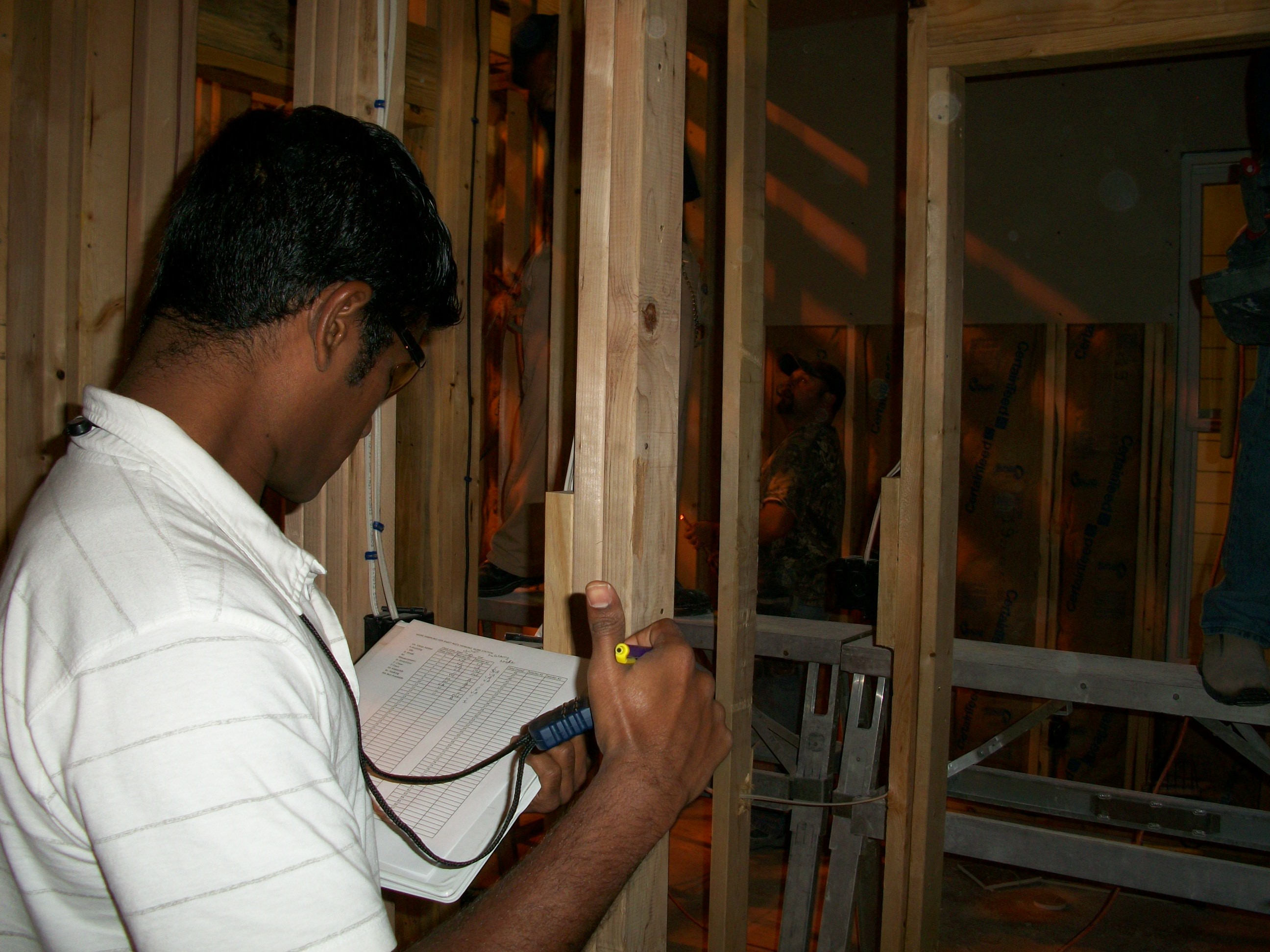 Picture of student taking and recording measurements on the internal framework of a building as part of a construction assessment study