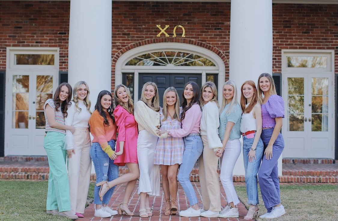 chi omega members in front of house