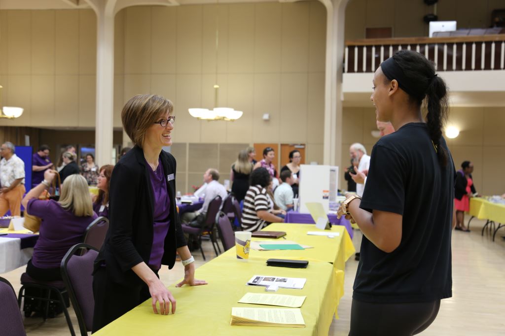 professor speaking with student at fair