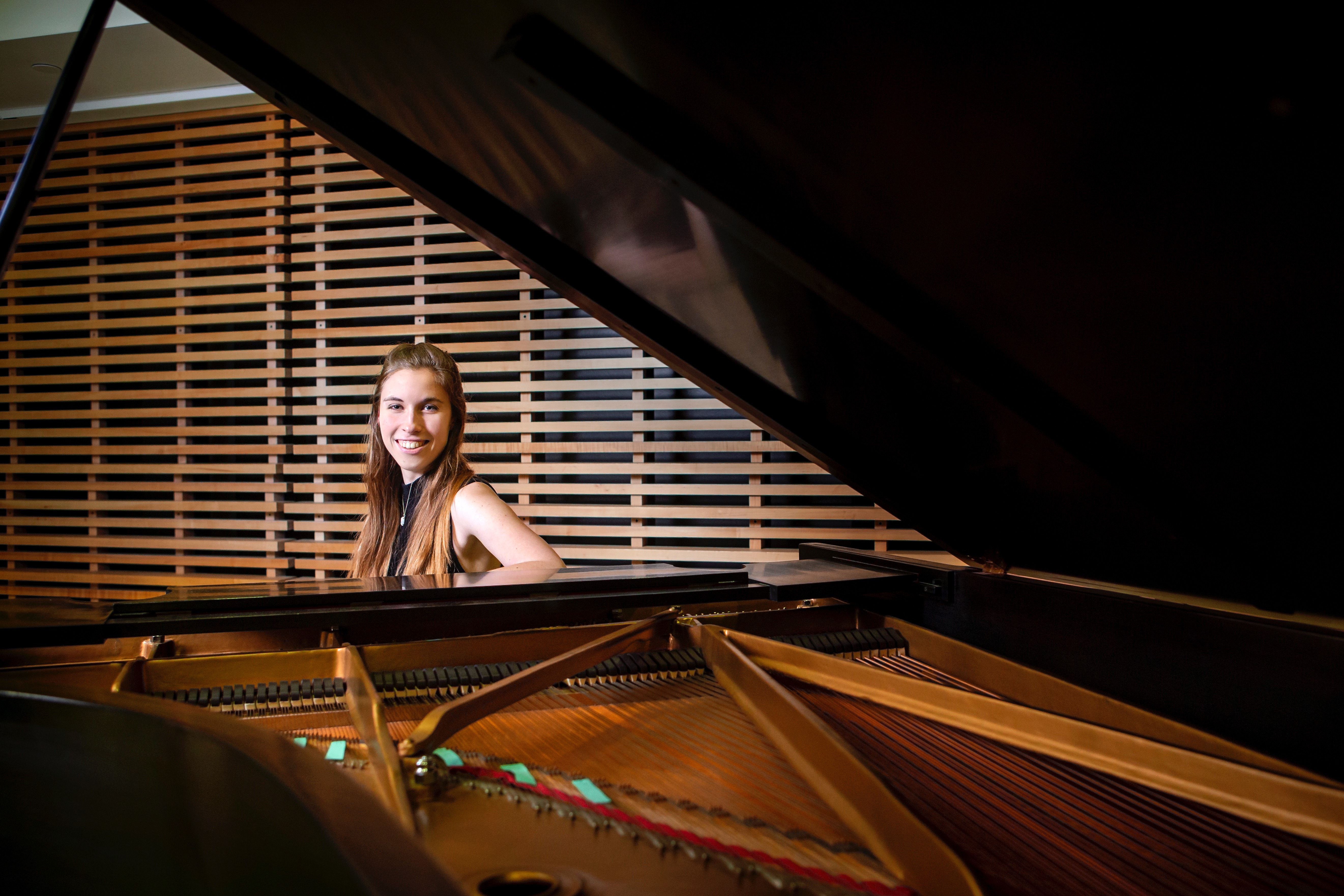 LSU student Katie Vukovics smiles while sitting at a piano.