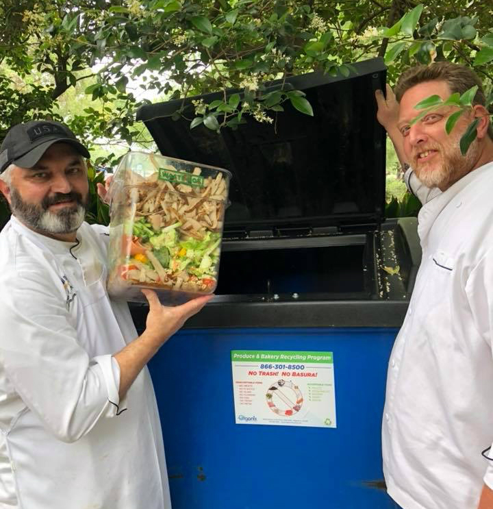 Two LSU Dining chefs depositing food scraps into food waste recycling dumpster
