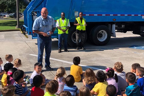 Man explaining recycling truck to preschool students